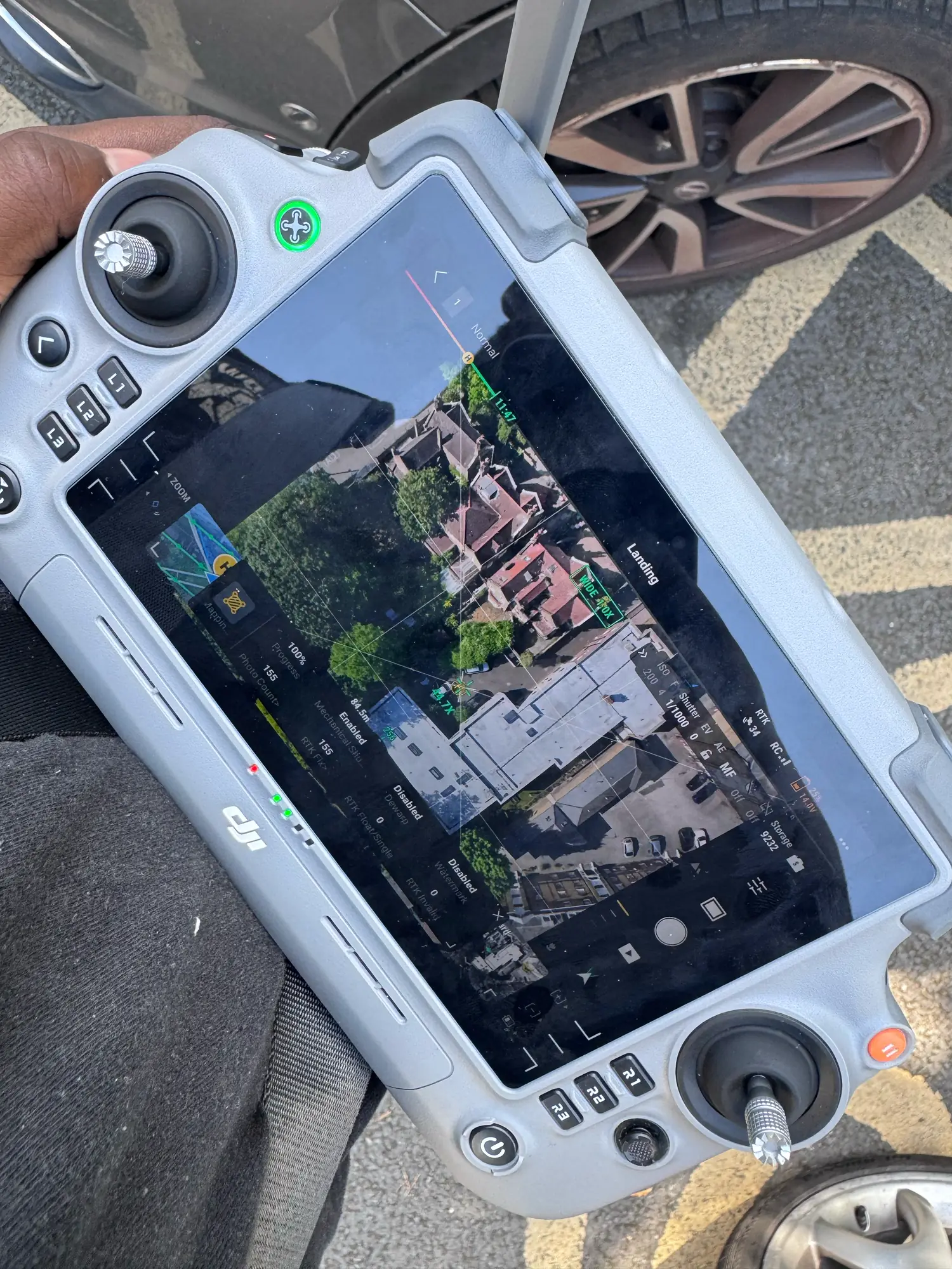 Pilot operating the DJI Matrice 4E controller during a live aerial survey flight over a London property